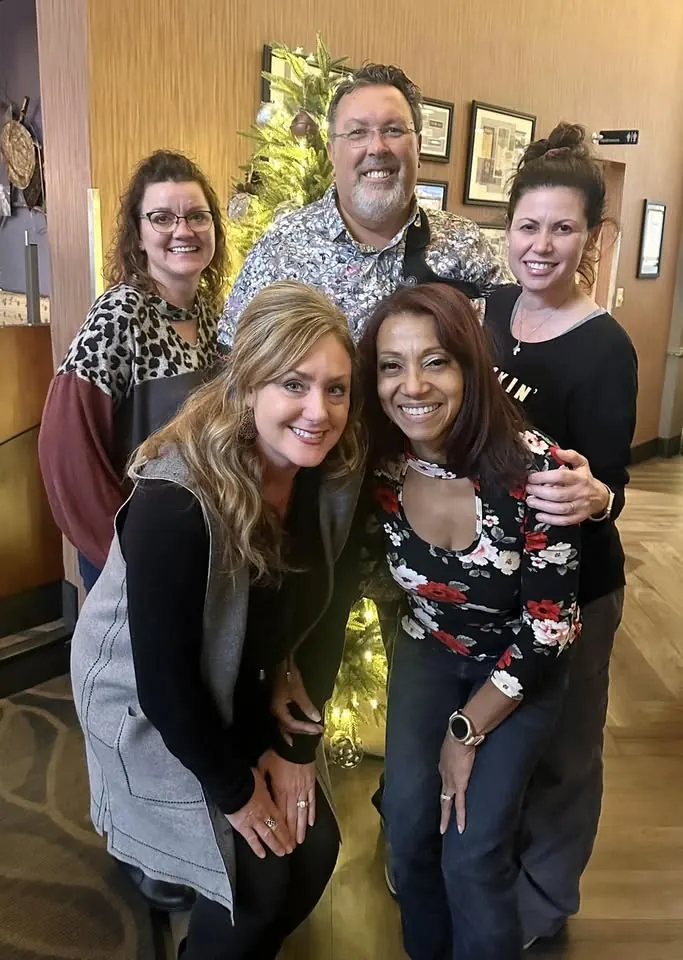 Dr. Mark Kolosionek with four members of the team, smiling together beside a Christmas tree.